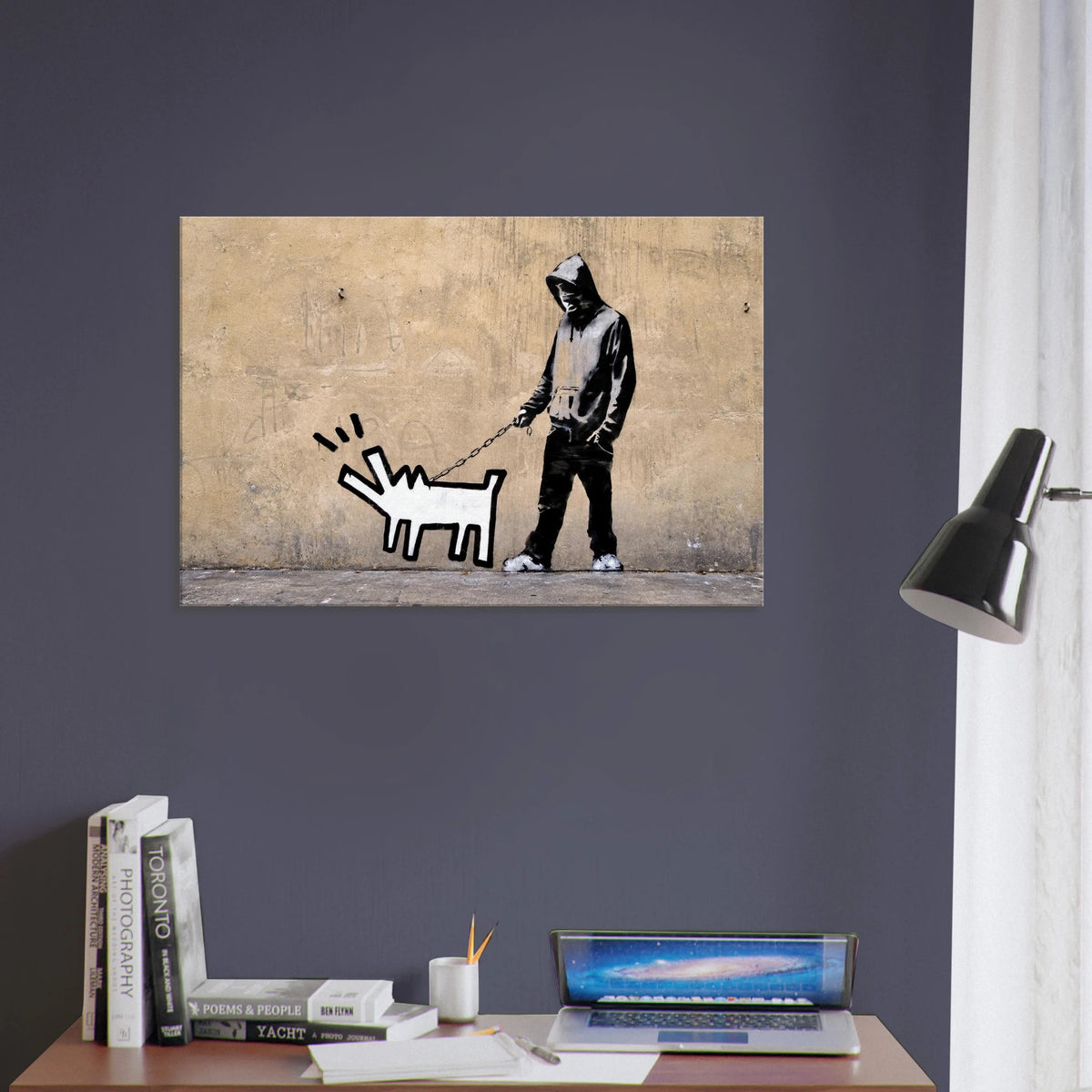 Banksy Choose Your Weapon canvas wall art displayed above a desk against a dark blue wall in a modern office.