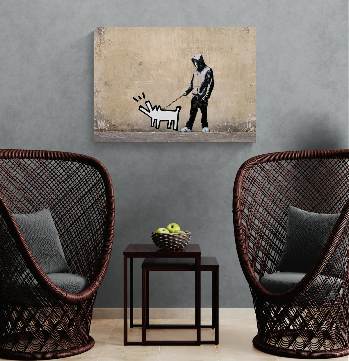 Banksy Choose Your Weapon canvas wall art featuring Keith Haring's barking dog displayed between two dark rattan chairs against a grey wall.