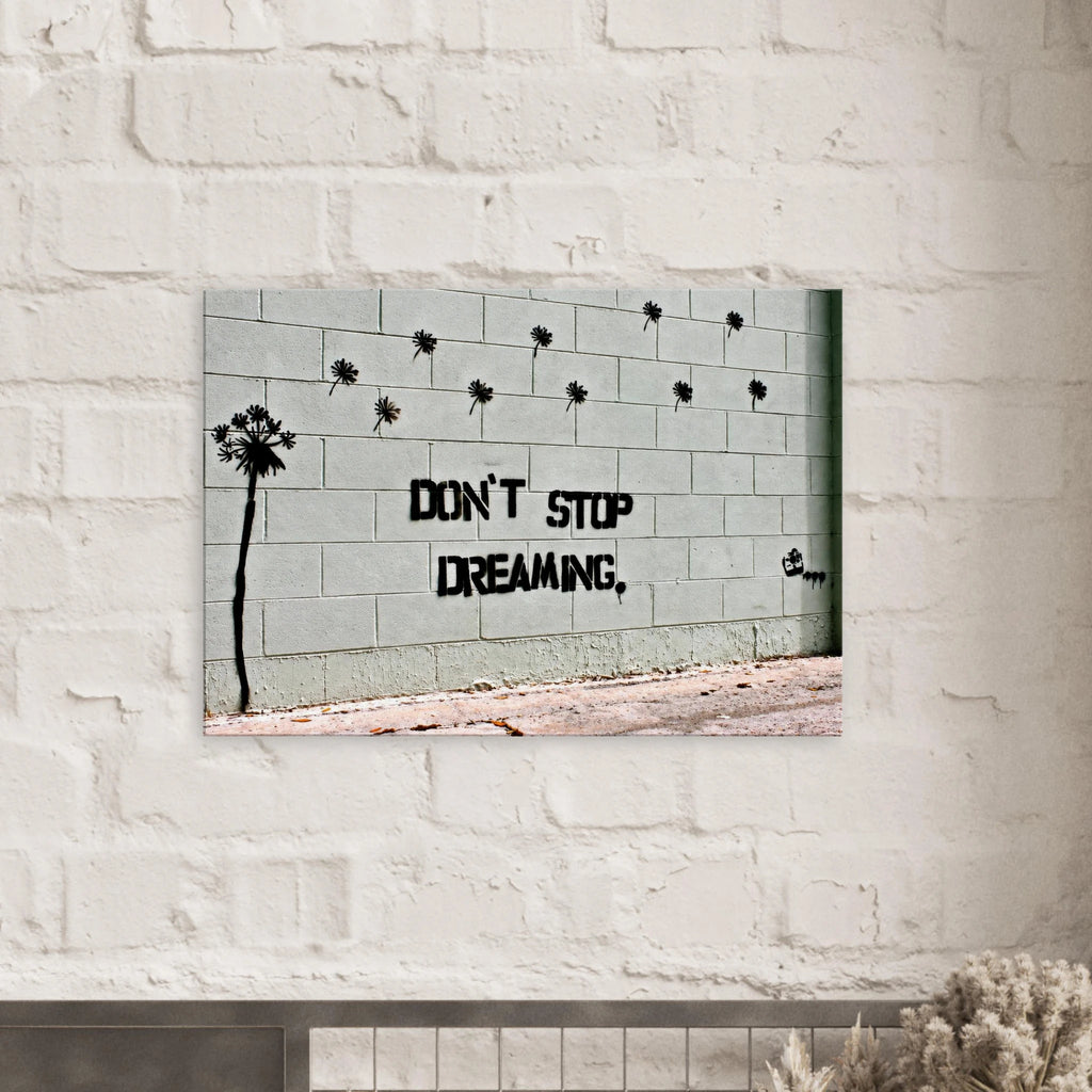 Banksy Don't Stop Dreaming canvas wall art displayed against a white brick wall.