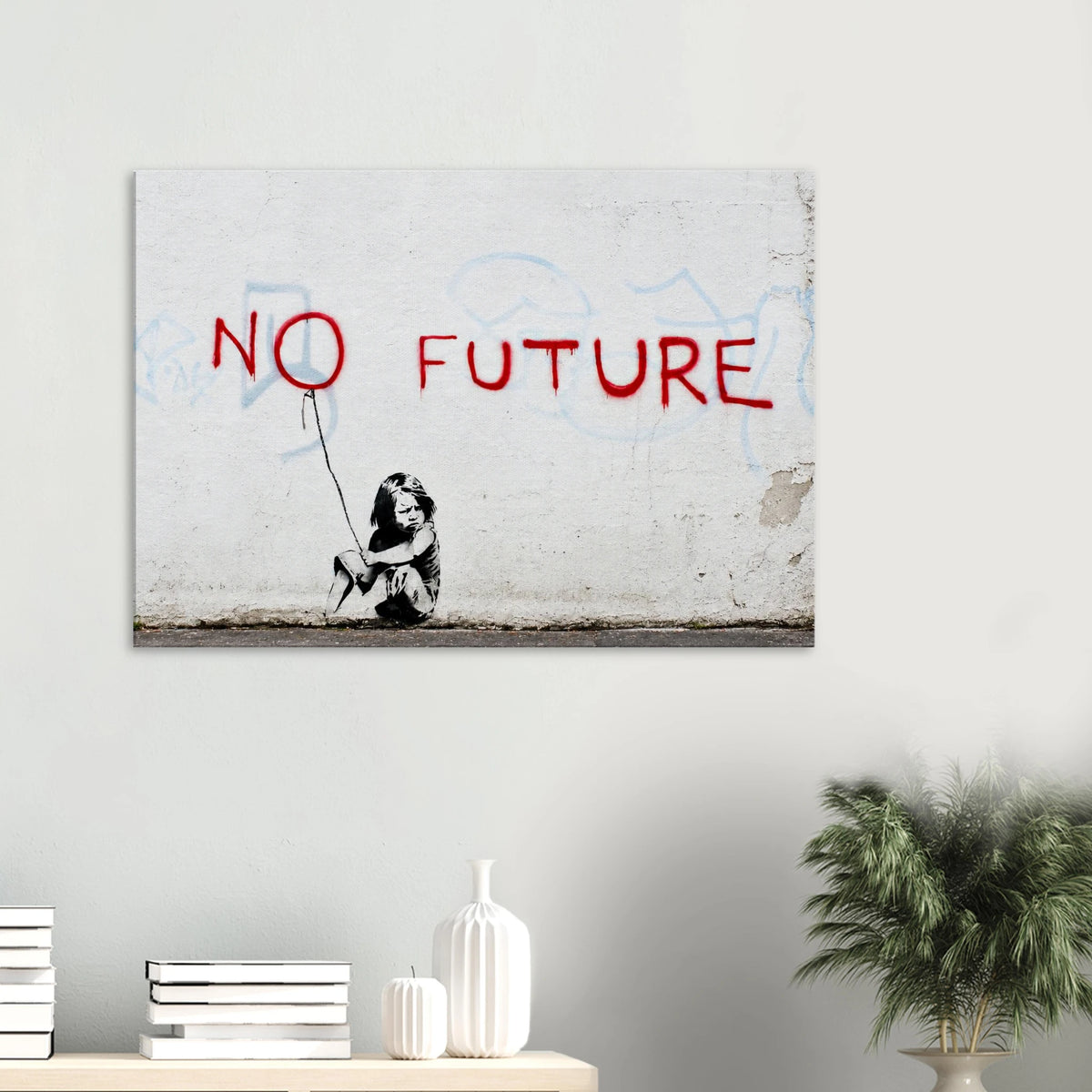 Banksy No Future canvas hanging above a white console with a green plant in a bright minimalist room