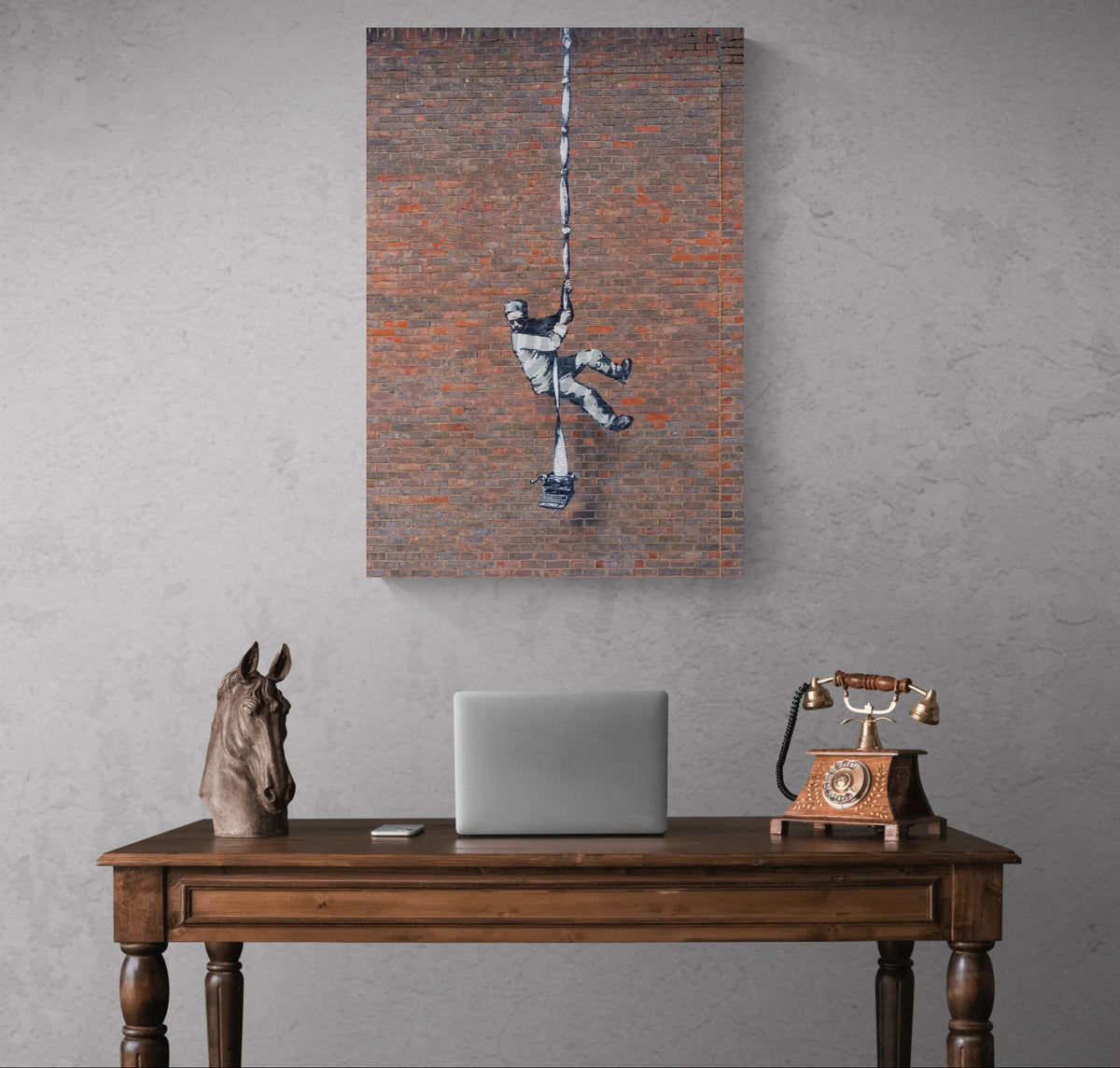 Banksy Prison Escape canvas wall art hanging above a wooden desk against a grey wall.